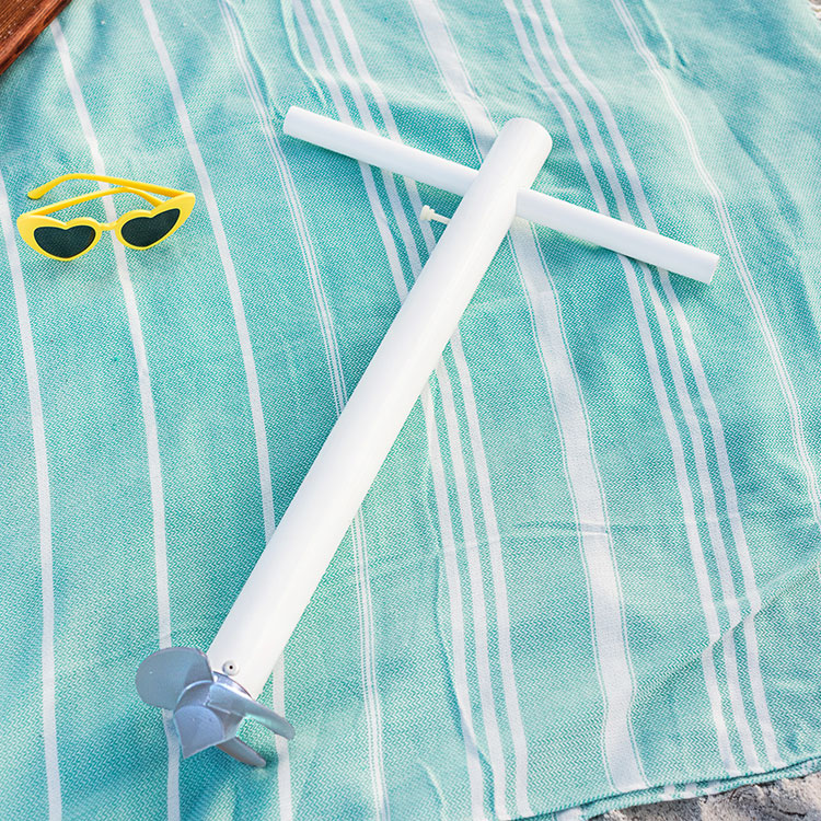 A product shot of the Suncoast Beach Shade umbrella anchor on top of a teal beach blanket with yellow heart sunglasses off to the side